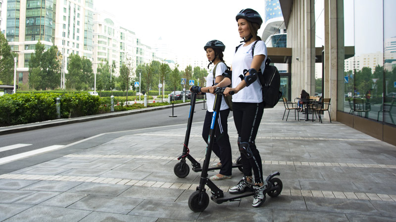Two people riding electric scooters